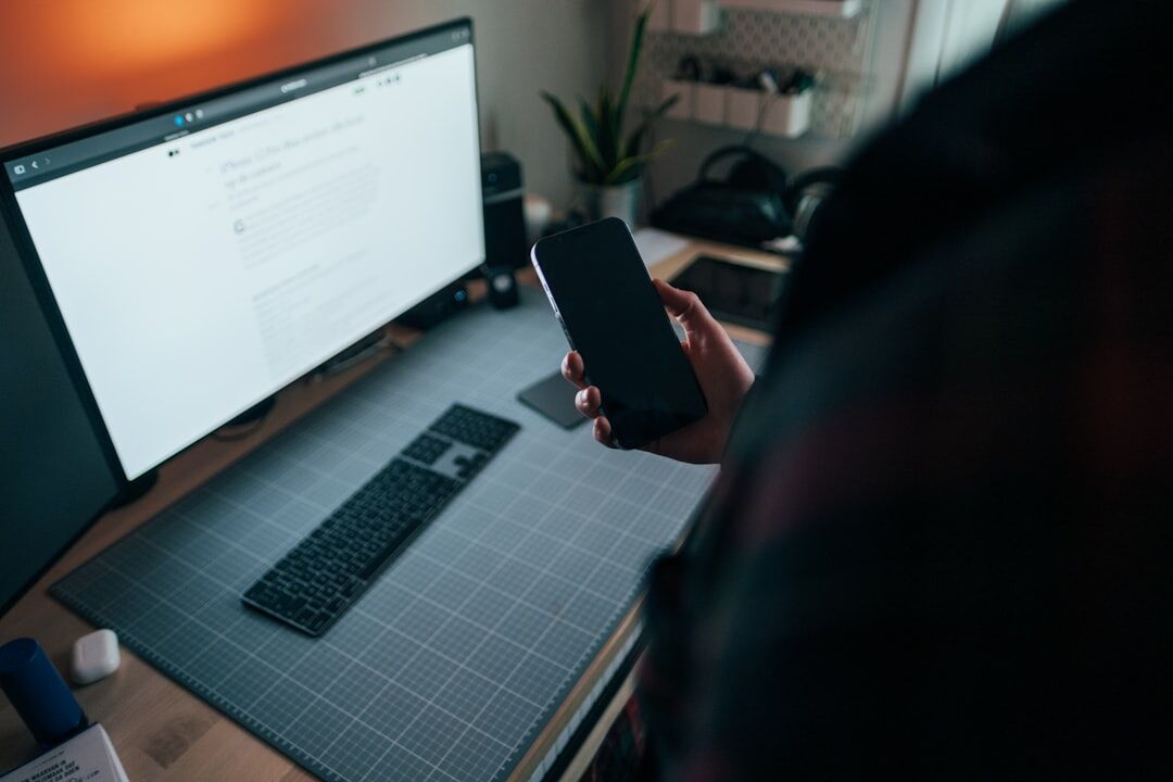 Belgian businesswoman working at a desk with a laptop and smartphone